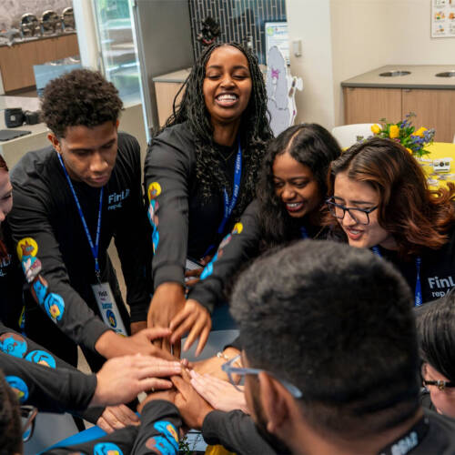 Students in a huddle with hands in